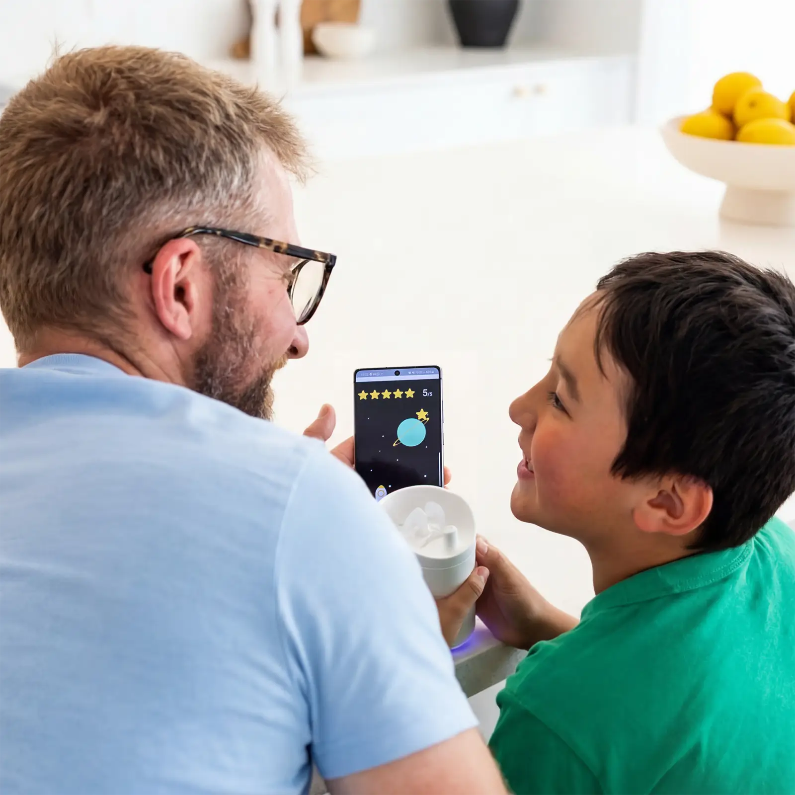 Parent holding Earflo mobile app sitting next to child holding Earflo device